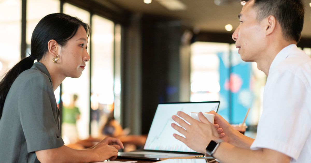 man speaking to woman in front of laptop