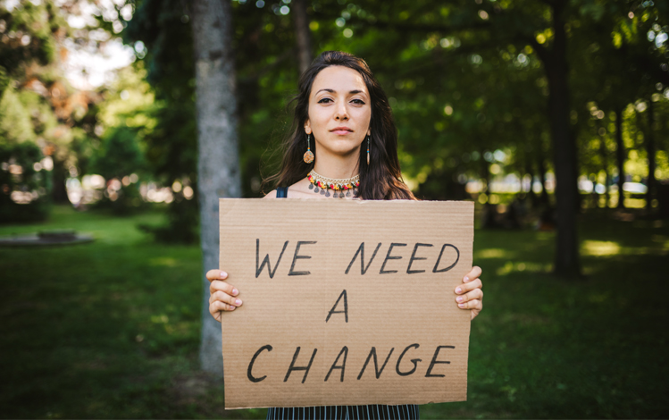 woman holding sign saying we need change