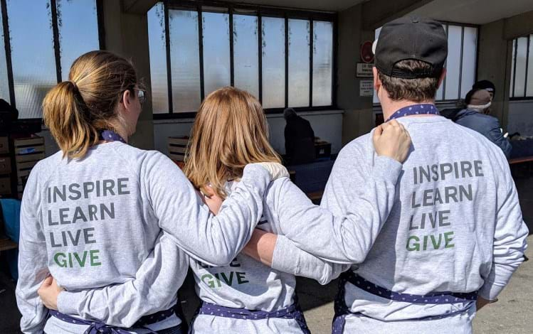 Group posing with inspire, learn, live, give shirts