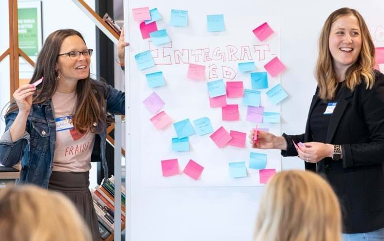 Two women brainstorming with sticky notes on a board